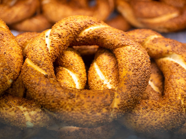 Simit - turkish bagels covered with sesame seeds are on the shop window behind the glass. Close-up. - Photo, Image