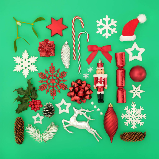 Divertente composizione natalizia con ornamenti ad albero, decorazioni a ciottoli, simboli e verde invernale su sfondo verde. Design astratto per le festività natalizie. Posa piatta, vista dall'alto. - Foto, immagini