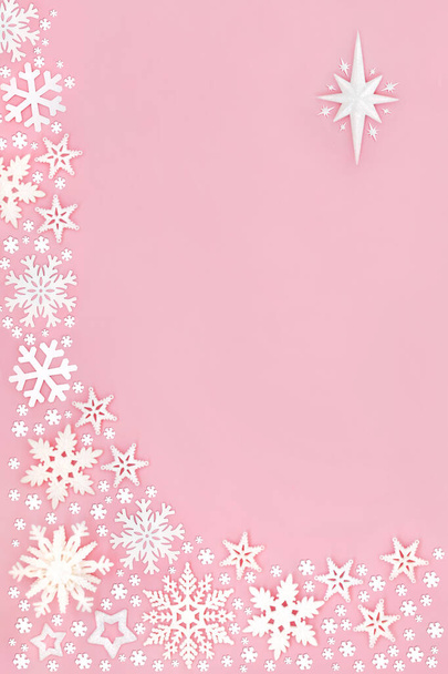 Copo de nieve de Navidad y borde abstracto estrella sobre fondo rosa pastel. Composición festiva para la temporada navideña. Vista superior plana, espacio de copia. - Foto, imagen