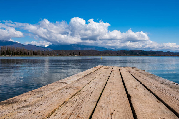wooden pier on the lake, blue cloudy sky and mountain landscape. beautiful view from the lake - Photo, Image