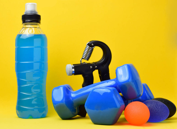 Hand grip fitness training, dumbbells and various accessories, on a yellow background. Copy space. - Photo, Image