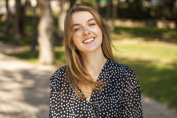 Close-up portrait of a teenage girl on the background of a city park - Zdjęcie, obraz