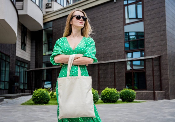 Молодая красивая женщина с льняной эко-сумкой на фоне города. - Фото, изображение