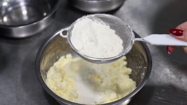 kucharze ręcznie przesiewa mąkę przez sito do miski z ciastem, pieczenia, widok z góry - Materiał filmowy, wideo