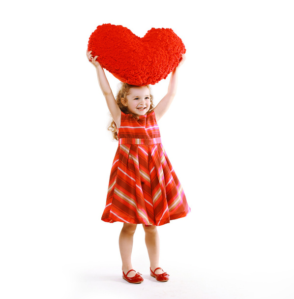 Cheerful charming little curly girl in a dress holding a heart - Фото, зображення