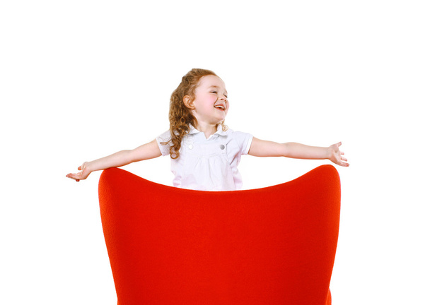 Joyful little girl in red chair - Foto, Imagen