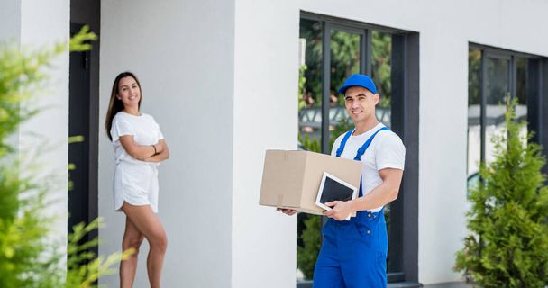 Young courier delivering goods to a young woman at home - Photo, image