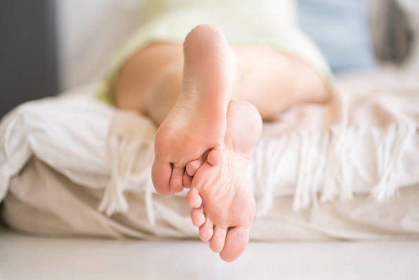 Woman relaxing in bedroom, female feet close-up, foot care concept, home interior - Foto, Imagen