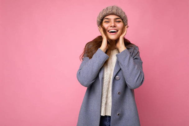 Attraente sorridente felice giovane donna bruna in piedi isolato su parete di sfondo colorato indossando ogni giorno vestito elegante che mostra emozioni facciali guardando la fotocamera - Foto, immagini