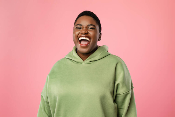 Plumpe Afroamerikanerin lacht laut über rosa Hintergrund - Foto, Bild