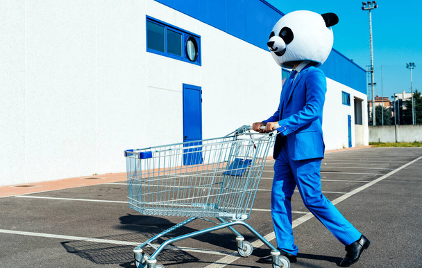 Storytelling image of a couple wearing giant panda head and colored suits. Man and woman making party in a parking lot. - Foto, afbeelding