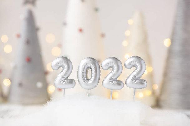 Silver number 2022 on nandmade Christmas trees background. Yarn wrapped cone trees and garland on background - Foto, imagen