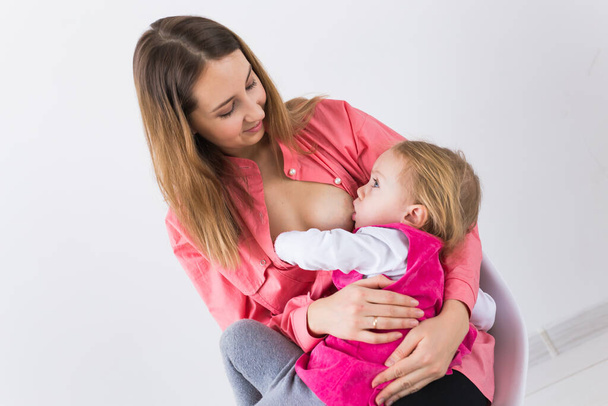 Motherhood and family concept - mother breast feeding and hugging her baby. - Foto, Imagem