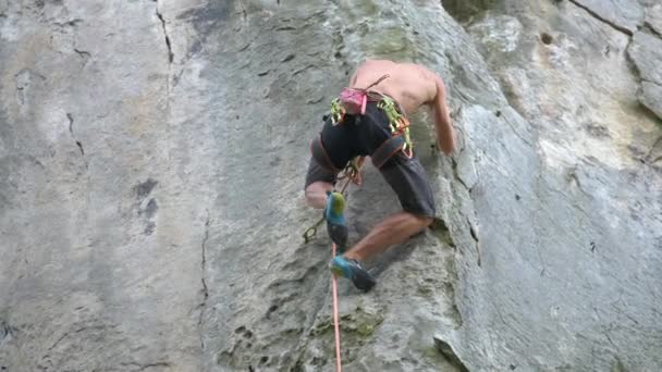Strong male climber climbing steep wall of rocky mountain. Sportsman overcoming difficult route. Engaging in extreme sports hobby concept - Footage, Video