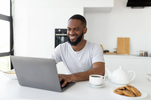 African American man using laptop in the kitchen - 写真・画像