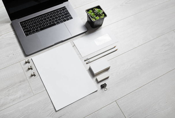 Foto van blanco briefpapier set en laptop op houten achtergrond. - Foto, afbeelding
