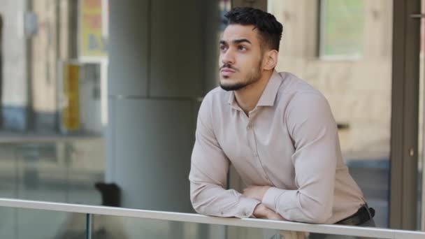 Hombre retrato hispano árabe guapo hombre de negocios en camisa formal jefe gerente trabajador empresario barbudo chico se para en balcón en edificio de oficinas empresa creativa pensando soñando disfrutar de la ciudad - Metraje, vídeo