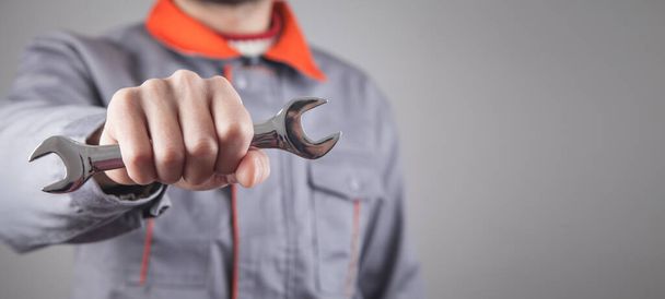 Man wearing a uniform holding a wrench. - Photo, Image