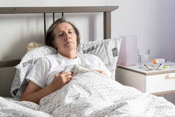 aging senior woman female in bed at home flat, tired sick ill alone retired and resting virus taking care unhappy sad. - Fotoğraf, Görsel