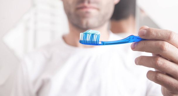 Uomo con dentifricio blu e spazzolino da denti. - Foto, immagini