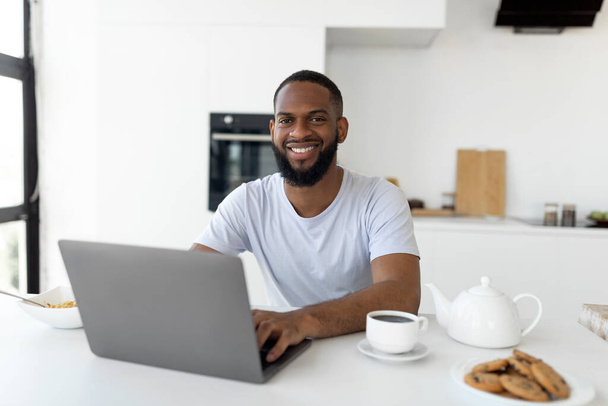 African American man using laptop in the kitchen - Фото, изображение