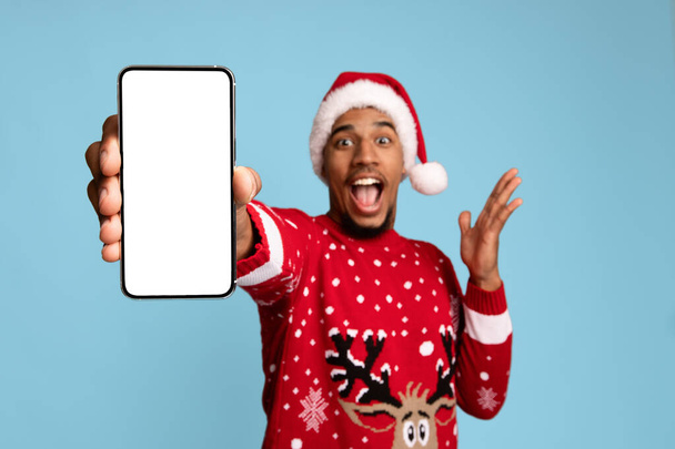 Emotionele Afro-Amerikaanse man in Santa hoed met mobiele telefoon - Foto, afbeelding