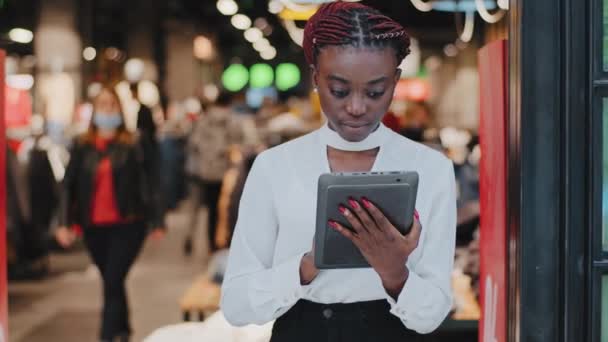 Afro americká seriózní úspěšný prodejce žena konzultant v obchodě s oblečením prodavač butik zaměstnanec hledá v digitálním tabletu dělá skladové účetnictví práce on-line čte informace o slevě - Záběry, video
