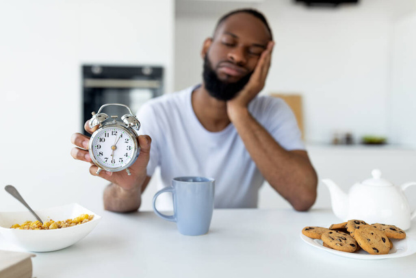 Homem negro sofrendo de insônia segurando mostrando despertador - Foto, Imagem