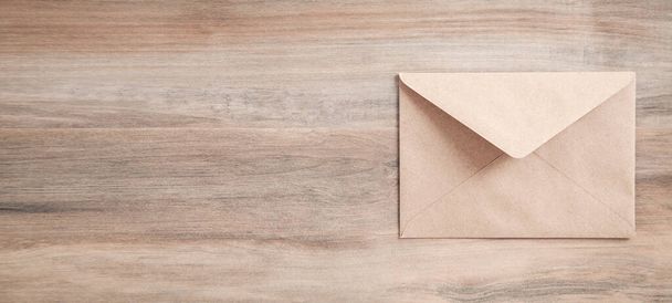 Коричневий поштовий конверт на дерев "яному тлі.. - Фото, зображення