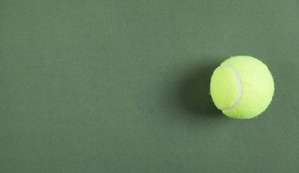 Tennis bal op de groene achtergrond. Ruimte voor uw tekst - Foto, afbeelding