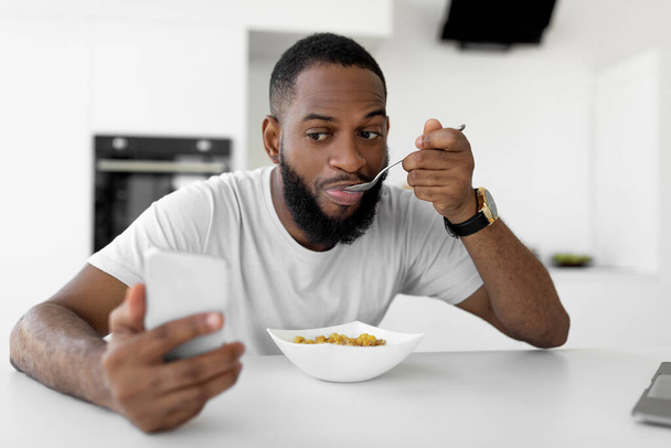 Siyah adam eve koşup mısır gevreği yiyor. - Fotoğraf, Görsel