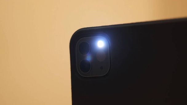 Detailní záběr chytrého telefonu, který pořizuje záblesk izolovaný na žlutém pozadí. Koncept. Blikající záblesk na zadní straně moderního mobilního telefonu.  - Fotografie, Obrázek