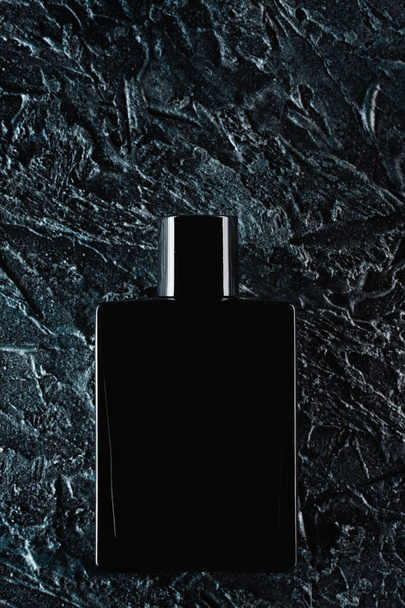Silhouette of a black bottle of eau de toilette for men on a dark background. Advertising photo of perfumes. Dark style - Fotó, kép