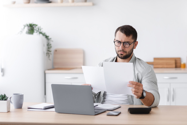 concentrado ocupado maduro caucasiano homem no óculos trabalho com documentos perto de laptop - Foto, Imagem