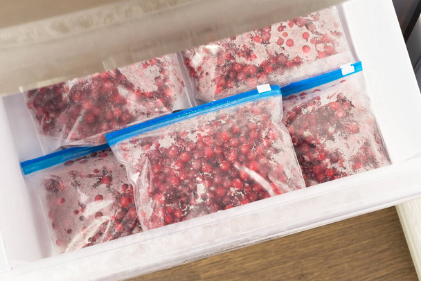 Bags of frozen cranberries in the freezer. - Foto, afbeelding
