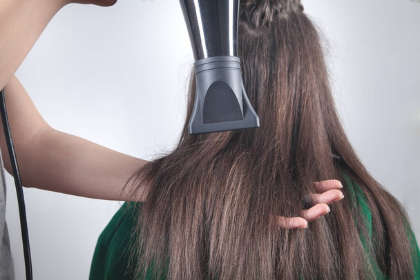 Girl drying hair with hairdryer in home. - Photo, Image