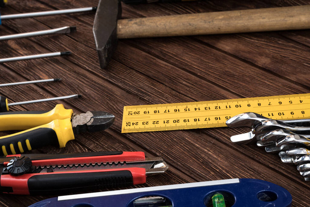 Locksmith's working tool. Mechanical assembly and disassembly tool. Screwdrivers, pliers, wire cutters, building level, tape measure, hammer, wrenches, square and other tools on a wooden surface. - Photo, Image