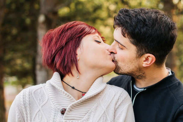 Young millennial couple, kissing in the park on valentine's day. - Photo, Image