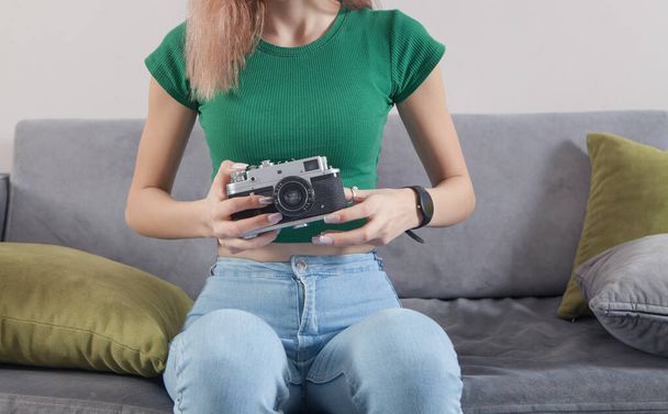 Καυκάσιος νεαρό κορίτσι κρατώντας παλιά κάμερα στο σπίτι. - Φωτογραφία, εικόνα