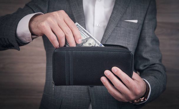 Businessman holding dollars with wallet. - Zdjęcie, obraz