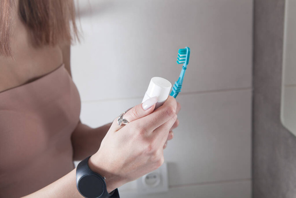 Dişlerini fırçalamadan önce elinde diş fırçası tutan genç bir kadın.. - Fotoğraf, Görsel