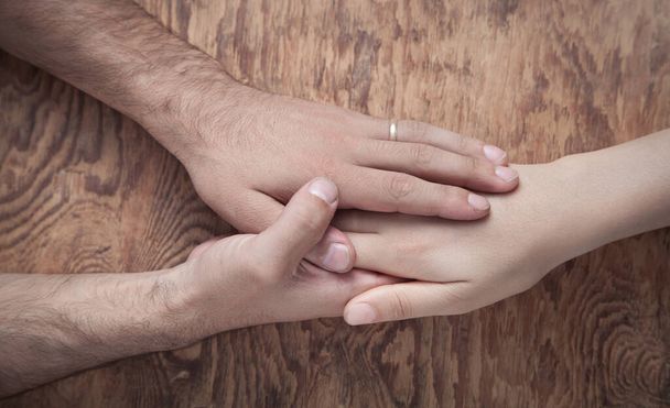 Young couple holding hands on wooden background. - Photo, Image