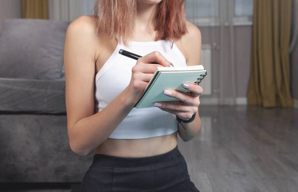Young woman writes training plans at home. - Fotó, kép