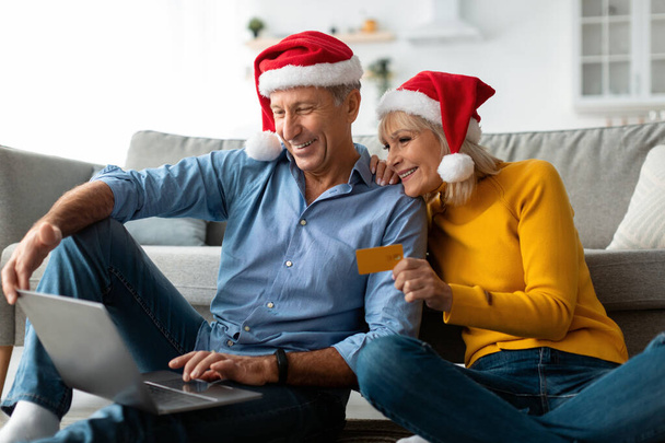 Зріла пара купує різдвяні подарунки використовуючи ноутбук вдома
 - Фото, зображення
