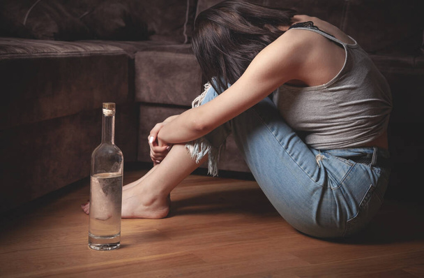 Jeune femme avec une bouteille de vodka à la maison. - Photo, image
