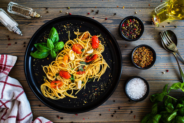 Spaghetti aglio e olio with parmesan, cherry tomatoes and basil on wooden table  - Photo, Image