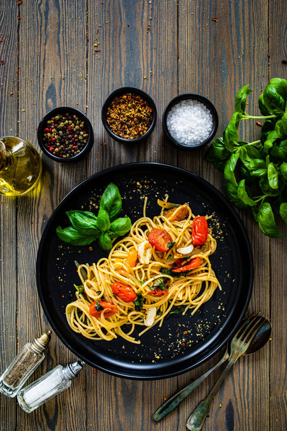 Spaghetti aglio e olio with parmesan, cherry tomatoes and basil on wooden table  - Φωτογραφία, εικόνα