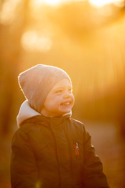 Мальчик в куртке улыбается на осенней улице - Фото, изображение