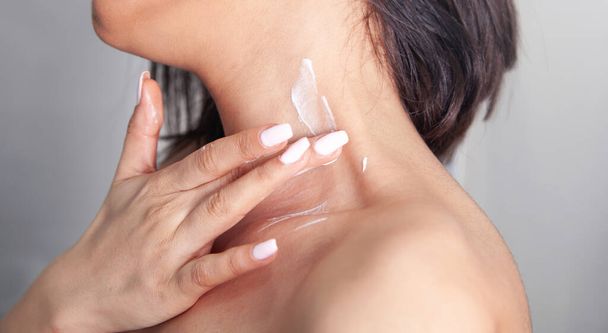 Vrouw verzorgen van haar lichaam aanbrengen crème. - Foto, afbeelding