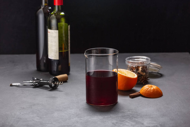 Alkoholischer Glühwein mit Früchten und Gewürzen auf dunklem Hintergrund, traditionelles alkoholisches Getränk, Weihnachten - Foto, Bild